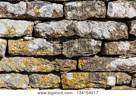 Old wall built of stones and covered with lichens close-up