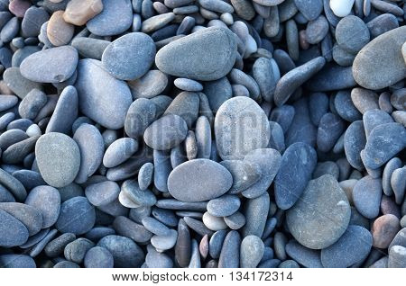 Round small sea of gray pebbles near the sea close-up