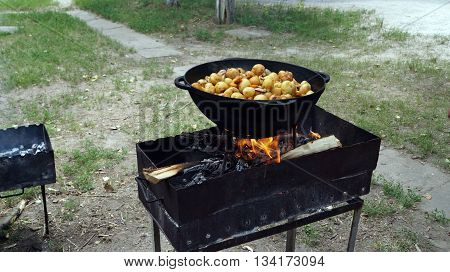 Potatoes cooked in a cast iron cauldron on the grill at a picnic