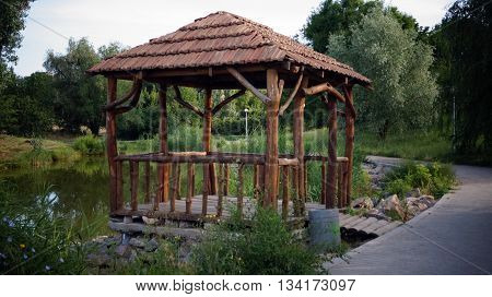 Wooden gazebo in the park by the lake summer afternoon