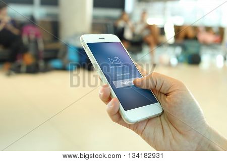Hand holding smartphone with member loging screen on airport background