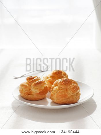 Profiteroles, choux with a custard cream, creme anglaise, whipped cream, dessert on a white plate Copy space