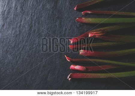 Organic red pieplant lying on dark stone