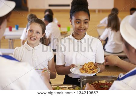 Over shoulder view of girls being served in school cafeteria