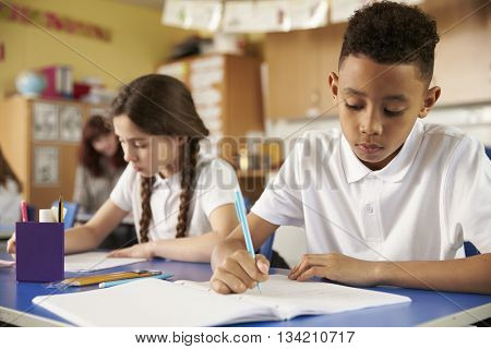 Two primary school pupils at their desks in class, close up