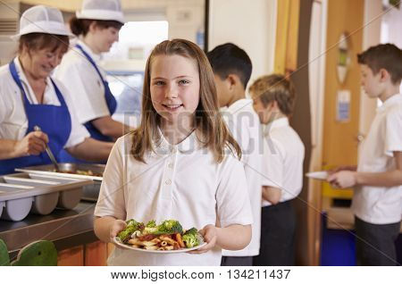 Schoolgirl holding a plate of food in a school cafeteria