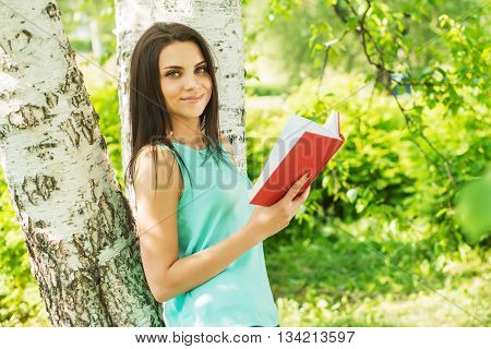 Girl in green park read book in summer sun ligh.