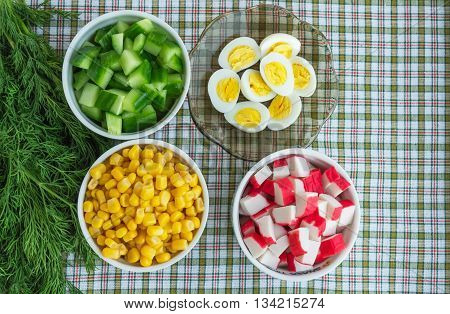 Many ingredients for the salad (sweet corn cucumber crab meat quail eggs) on a light background. The top view