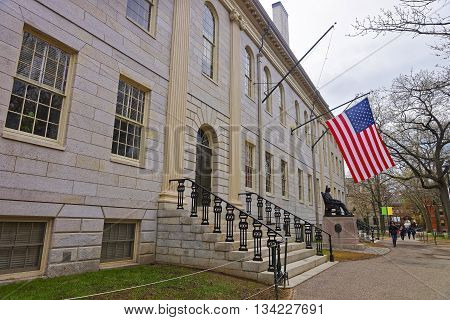 Cambridge, USA - April 29, 2015: University Hall and John Harvard Monument in the campus of Harvard University of Cambridge Massachusetts MA USA. It is a well-known statue of the University founder in America. Tourists in the yard