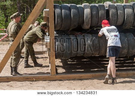 Tyumen Russia - June 11 2016: Race of Heroes project on the ground of the highest military and engineering school. Sportsmen move between old tires. Human birth stage
