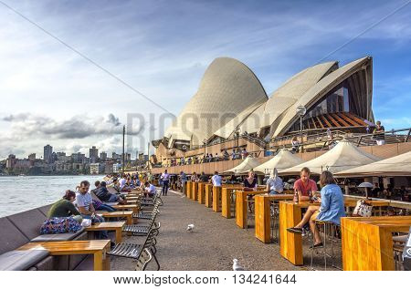 Tourists Sitting In Opera Bar In Front Of Sydney Opera House
