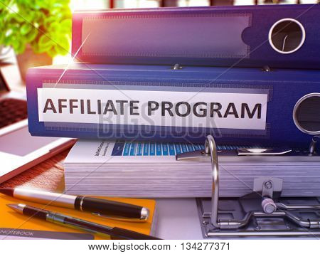Blue Ring Binder with Inscription Affiliate Program on Background of Working Table with Office Supplies and Laptop. Affiliate Program Business Concept on Blurred Background. 3D Render.
