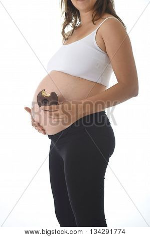 young pregnant woman holding her big belly with hand and eating chocolate donut happy isolated on white background in pregnancy whim food concept isolated on white background