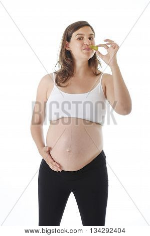 young attractive pregnant woman holding her big belly in one hand and eating pickle happy isolated on white background in pregnancy whim food concept isolated on white background