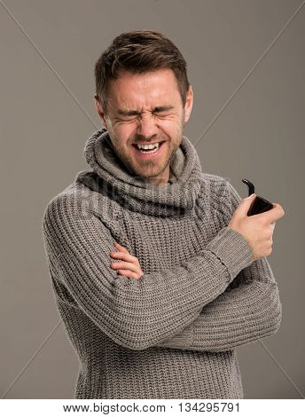 Man laughing with a pipe in his hand, studio, gray background.