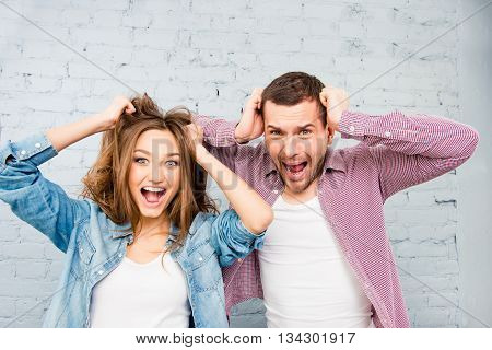 Portrait Of Young Man And Woman Screaming And Touching Hair