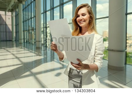 Businesswoman hold some documents against a big window. Image with split toned techniques