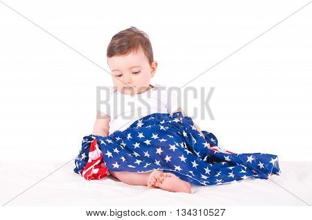 Baby girl with american flag on white sofa.