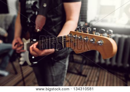 Bass guitar in playing musician hands close-up. Focus on bass guitar neck in player hands. Unrecoginzable bass guitar player performing at music studio, blurred background