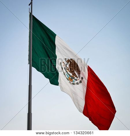 National flag of Mexico with the blue sky background flying over Zocalo square in Mexico city