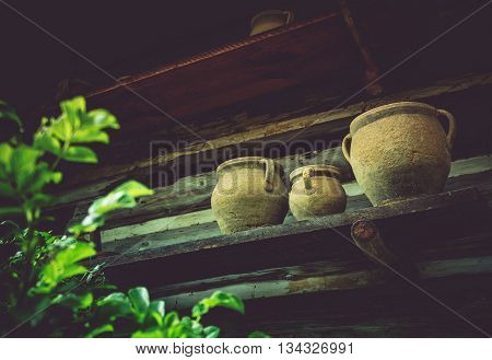 Vintage Earthenware on a Shelf Outside of Old Log Cabin. Aged Ceramic Crocks.
