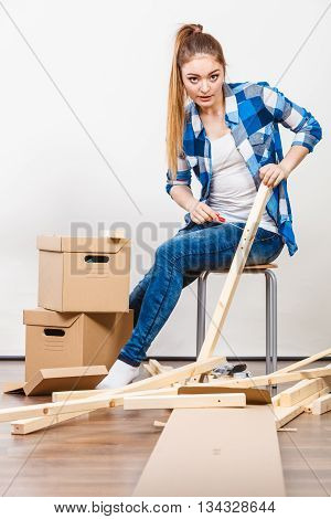 Woman Moving Into Apartment Assembly Furniture.