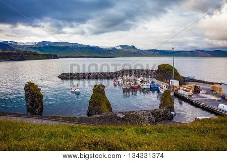 Sunset on the fjord in Iceland. White and red fishing boat in the harbor pier village Arnastapi