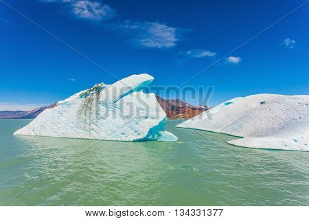  The huge white-blue iceberg drifts from coastal glacier in warm summer day. Argentina Patagonia, Lake Viedma