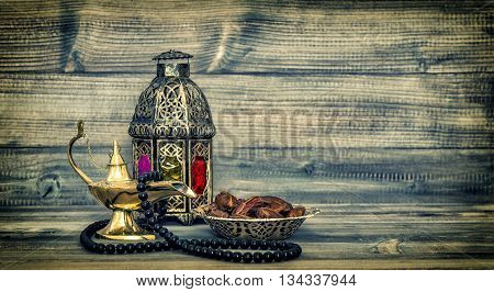 Antique arabic lantern and islamic rosary beads. Oriental holidays decoration with dates fruits. Vintage style toned picture