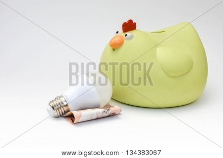 LED bulb and yellow chicken piggy bank on white background - Saving Technology