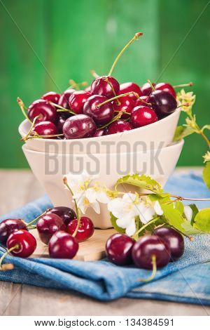 ripe raw dark red cherrys with white flowers on blue textile