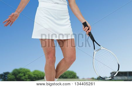 Athlete playing tennis with a racket against tracks on a sunny day