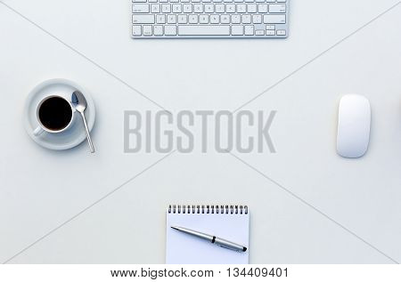 Bright Open Space Office White Table Top View with Coffee Mug Opened Blank Notepad Pen and Computer Keyboard and Mouse on Desk