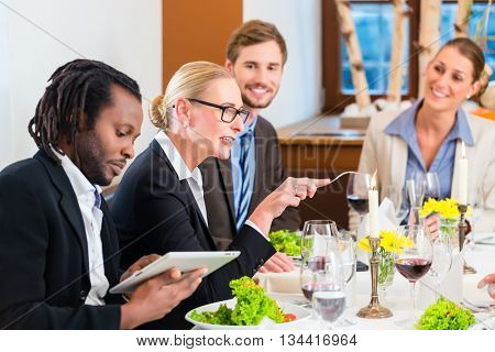 Team at business lunch meeting in restaurant eating and drinking in celebration of good work together, food and drink on the table in background