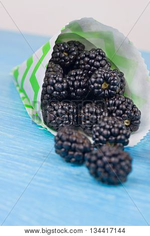 Blackberries in cup on a wooden table. Macro image.selective focus