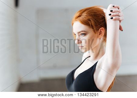Close-up portrait of a beautiful young fitness woman streching at the gym