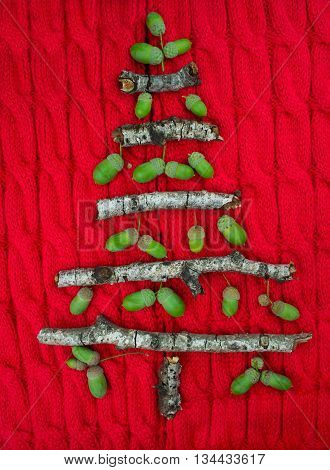 Christmas warm knitted background with new year tree decorations made of sticks and acorns. Vintage christmas card with handmade christmas tree. X-mass concept.