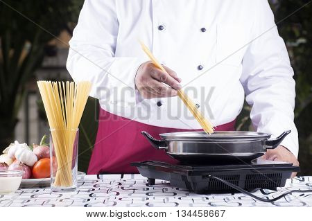 Chef putting spagetti to boiled in the pan / cooking spagetti concept