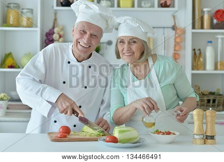 Portrait of a senior couple at kitchen cooking