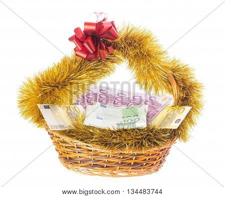 Wicker basket full of euro bills with christmas golden tinsel and red ribbon. Isolated on a white background.