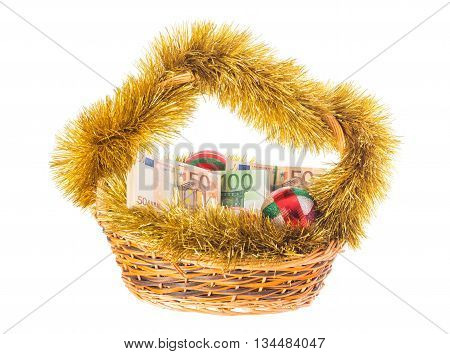 Wicker basket full of euro bills with christmas golden tinsel and bright Christmas balls. Isolated on a white background.