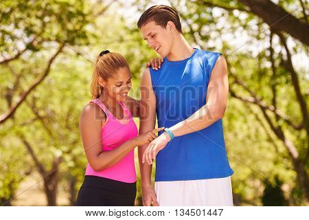 Young people doing sport activities girl and friend running man and woman using fitness watch. 