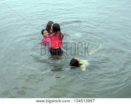 CEBU CITY, CEBU / PHILIPPINES - JULY 30, 2011: Children play in the water at a public beach in Cebu.