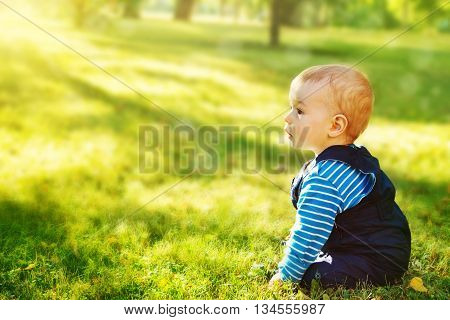 little nine month old baby sitting in the park in beautiful evening