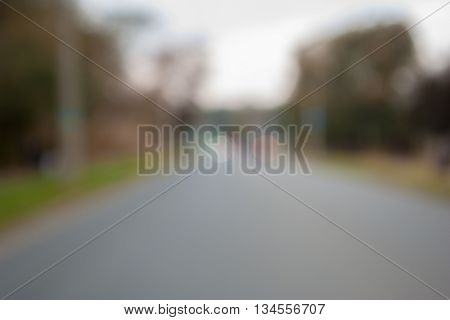 Blurred background. Evening city photo with lights and blur. Blurry photo of the road with traffic lights in the distance and trees at the sides.