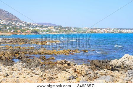 Rocks on the shore of the sea and the city of Hersonissos Crete Greece.