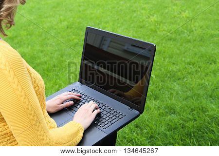 Young Caucasian woman using Laptop on nature sitting on a bench