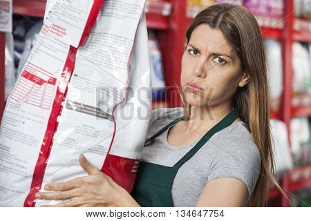 Saleswoman Carrying Heavy Food Package In Pet Store