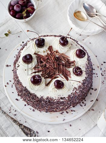 Black forest cake decorated with whipped cream and cherries Pie dark chocolate and cherry dessert on a white plate