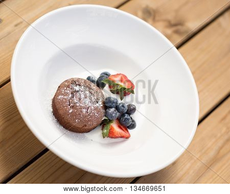 Chocolate fondant served with bilberries strawberries and ice cream.